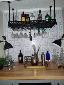 A mini bar with a suspended shelf from the ceiling and different drinks
